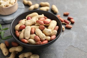 Fresh unpeeled peanuts in bowl on grey table